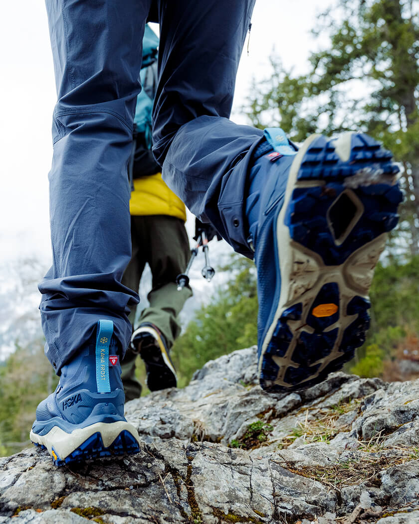 Close-up of a hiker's boots and legs climbing rocky terrain.