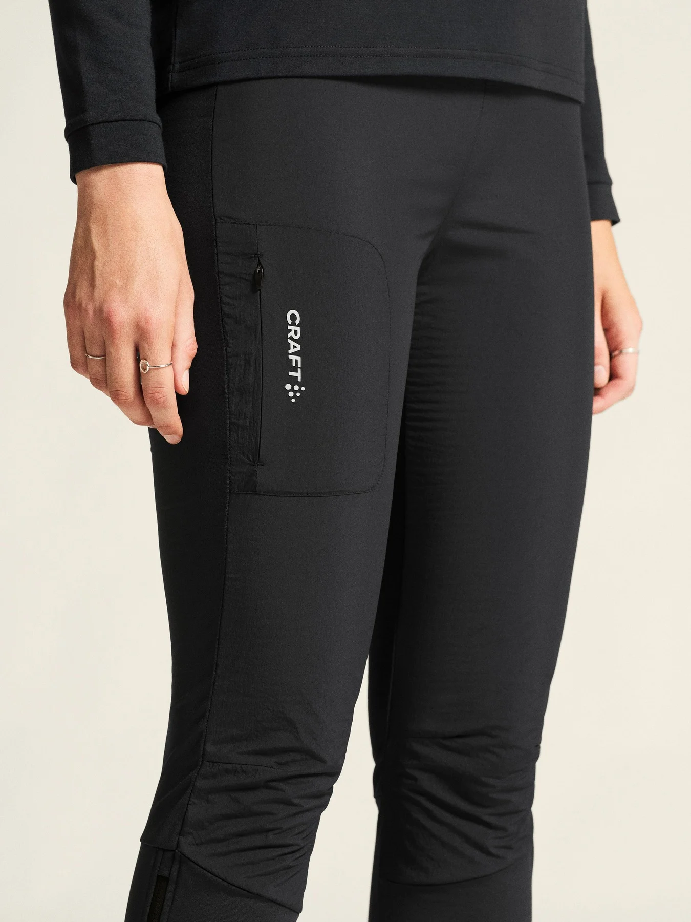 Close-up of black Craft leggings with a side pocket and logo.