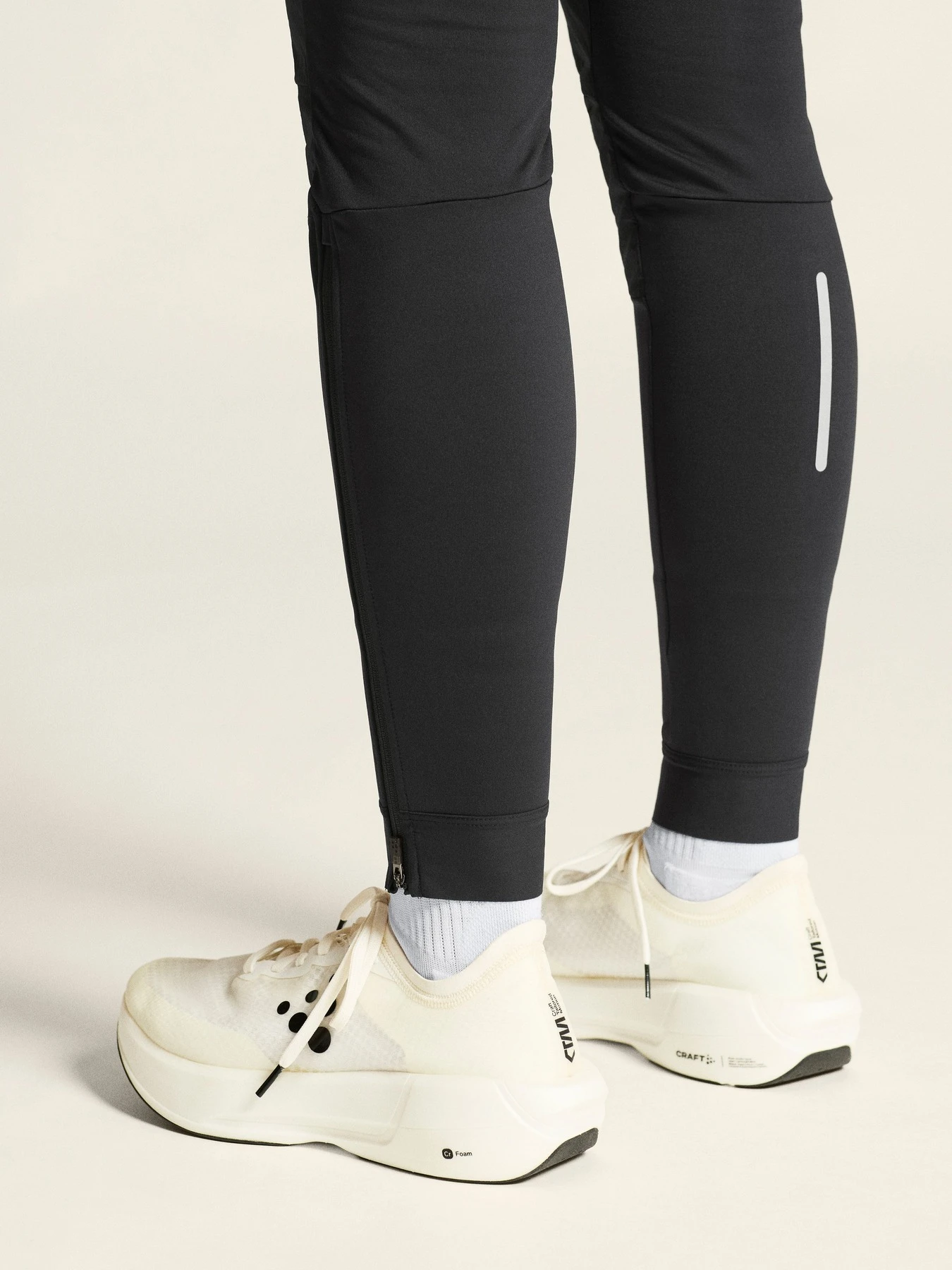 Close-up of black leggings with a reflective strip and white sneakers.