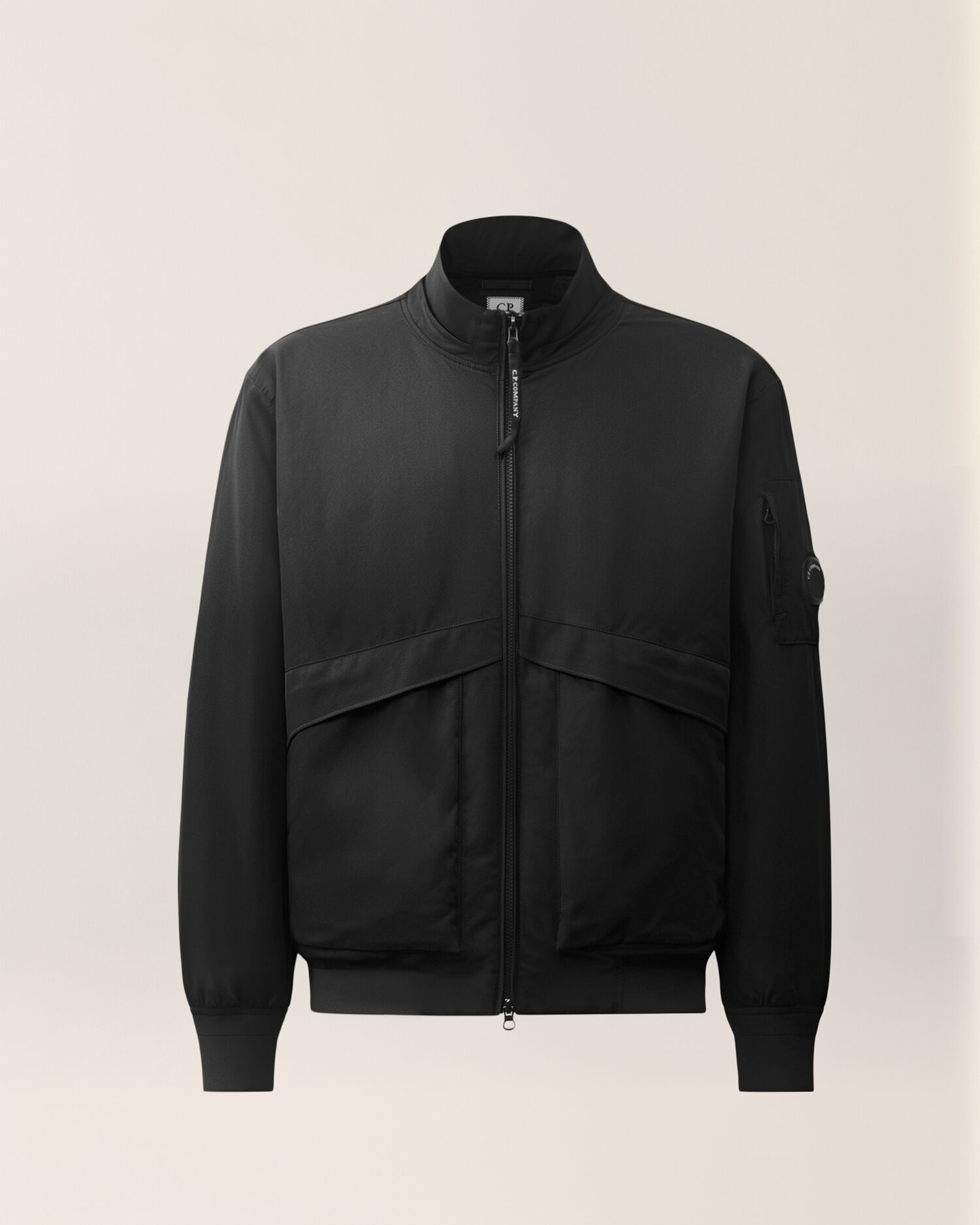 Black C.P. Company bomber jacket with a lens detail on the sleeve, product shot.