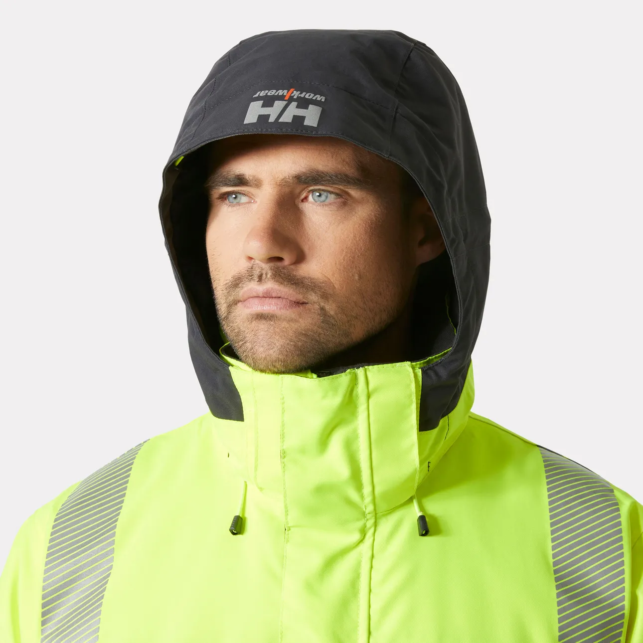 Close-up of a man's face under the hood of a yellow Helly Hansen Workwear jacket.