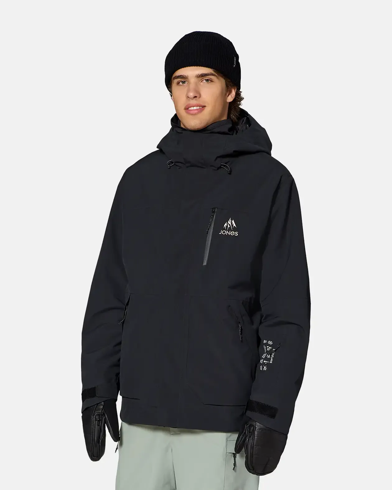 Man wearing a black Jones Snowboards hooded jacket, beanie, and mittens, front view.