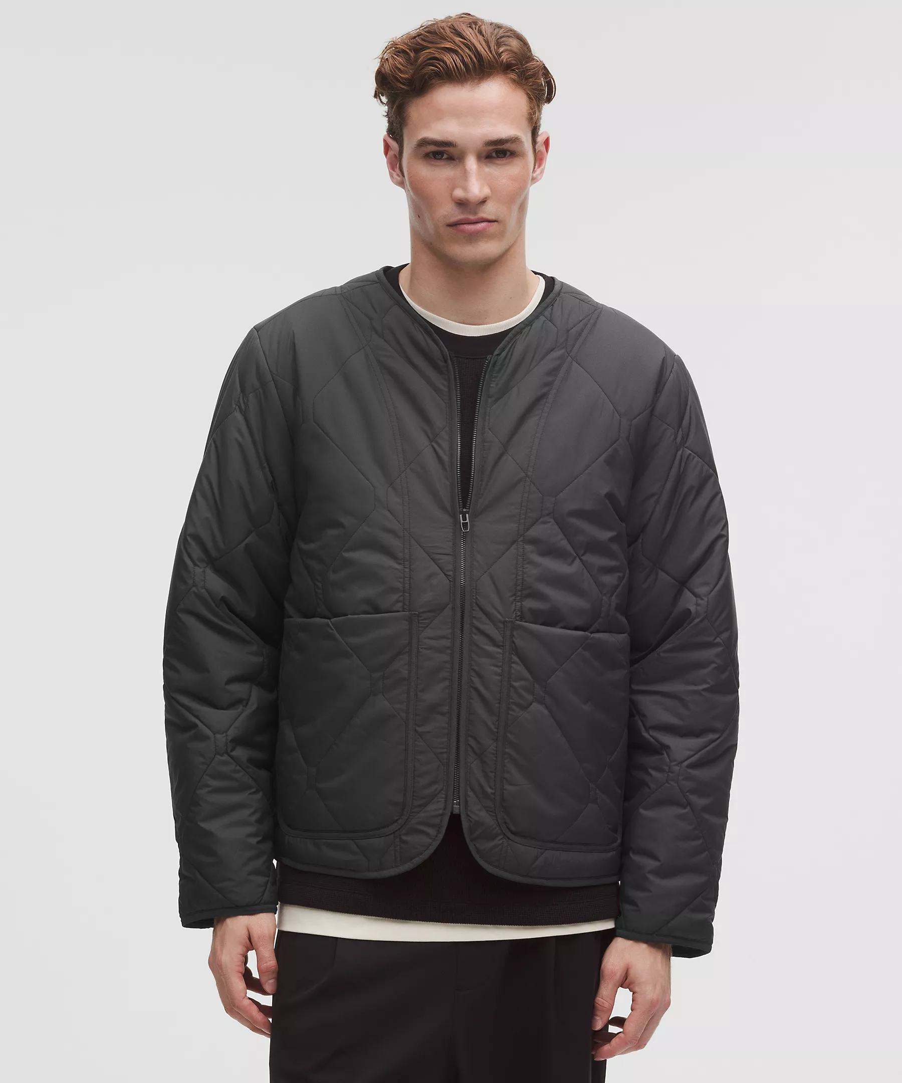 Man wearing a black diamond-quilted collarless jacket, front view.