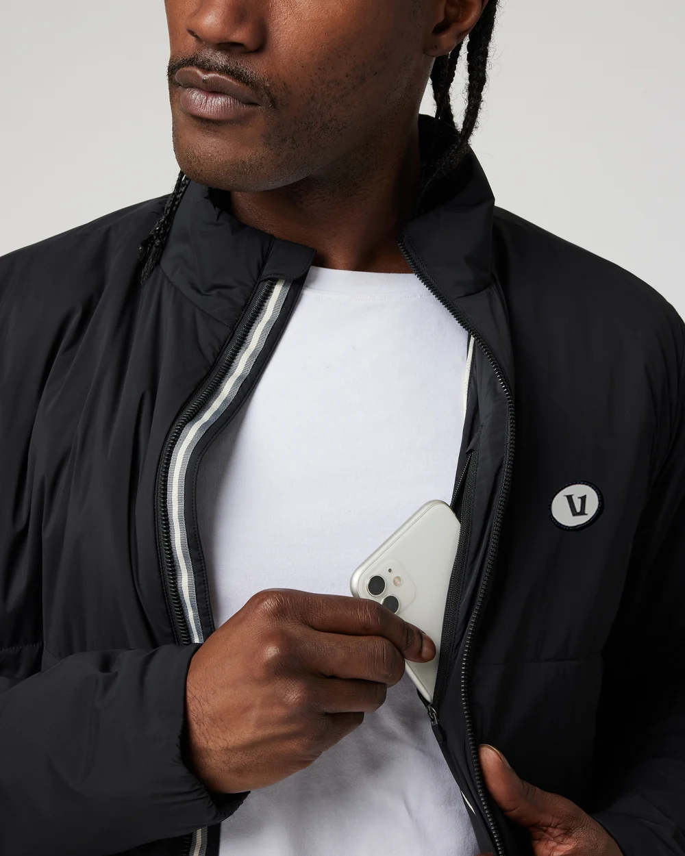 Close-up of a man pulling a phone out of the chest pocket of a black Vuori jacket