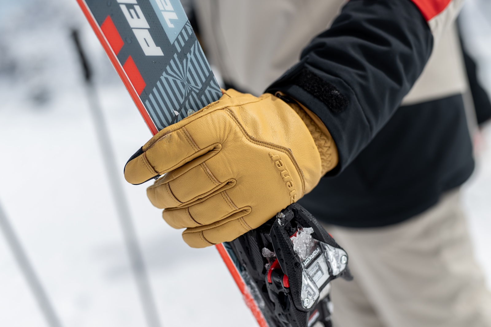 Close-up of a hand wearing a tan Ziener leather glove gripping a ski.