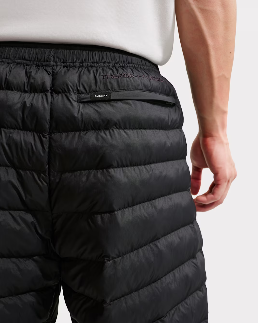 Close-up of a black quilted pants waistband, back view.